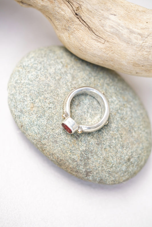Bright red sunstone silver ring on a piece of river rock