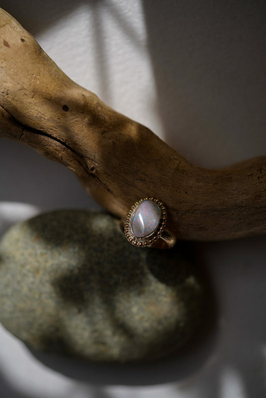 Gold ring with a opal stone on a gray stone surface