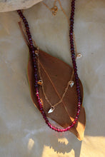 Load image into Gallery viewer, Necklace with red beads and gold accents on a leaf
