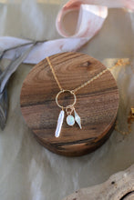 Load image into Gallery viewer, Gold necklace with pearl, opal and starburst shape pendants on a wooden surface