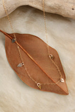 Load image into Gallery viewer, Gold necklace with gold pendants on a brown leaf and stone background