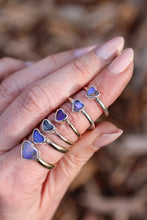 Load image into Gallery viewer, Hand wearing multiple gold and silver rings with heart-shaped opal stones against a blurred natural background