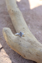 Load image into Gallery viewer, Silver ring with a vintage component design next to two baguette diamonds on a piece of driftwood on a stone surface