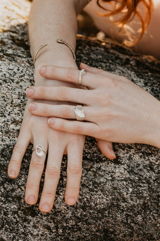 Two hands with rings on a rocky surface