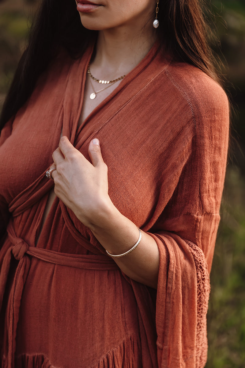 a women in a orange dress, wearing gold jewelry 