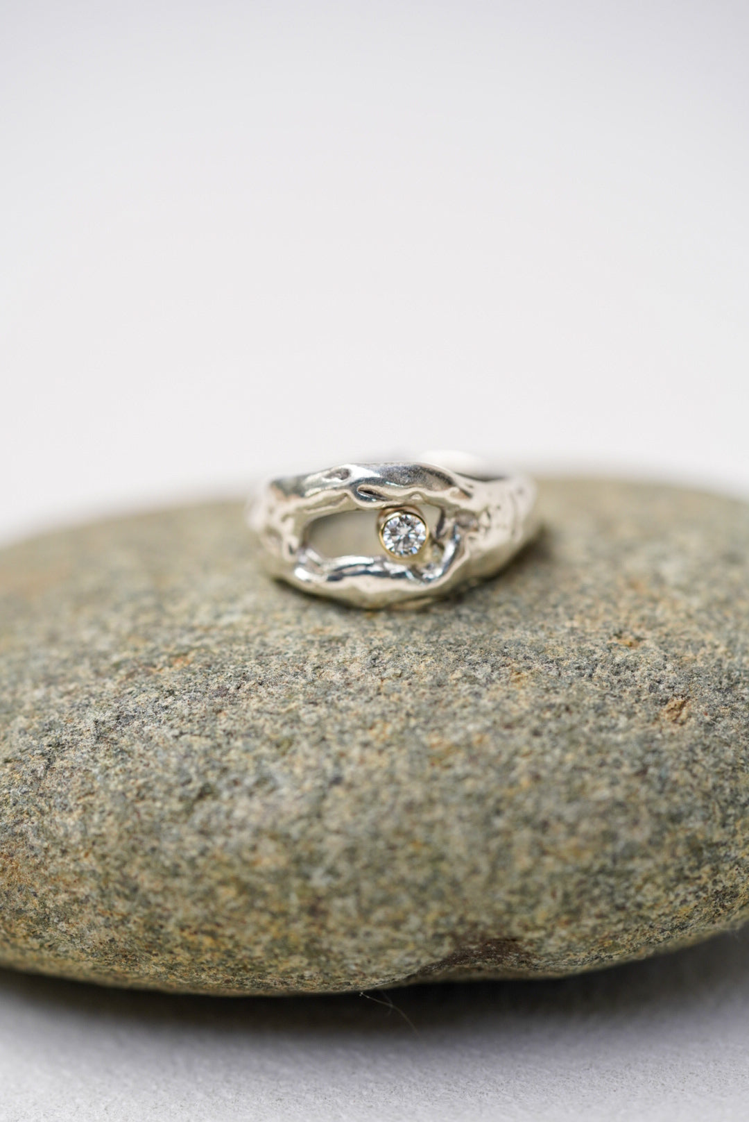 Silver ring with a diamond on a gray stone surface