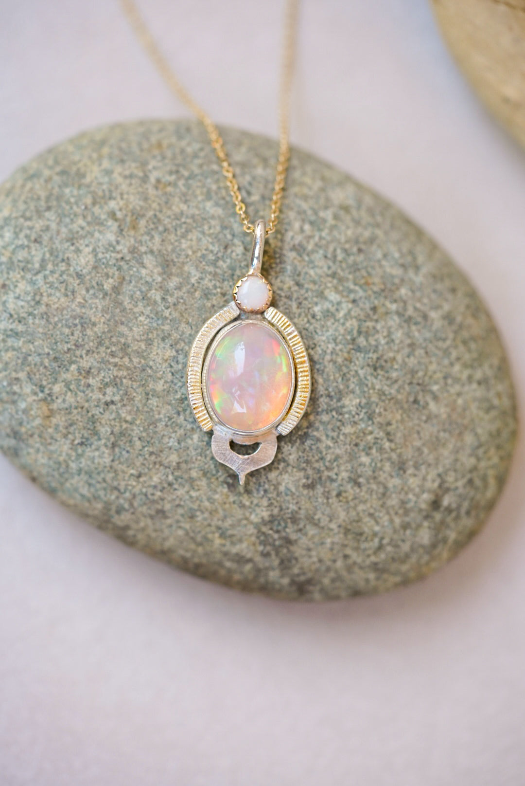 Opal pendant necklace on a stone surface