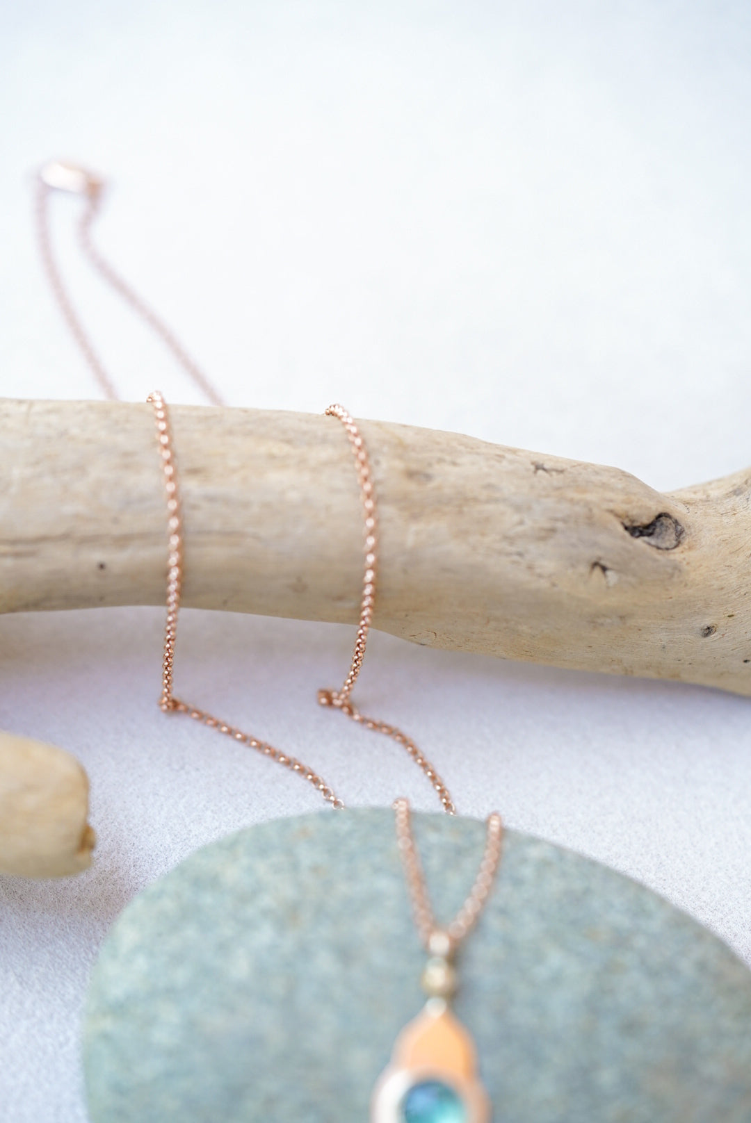 Close-up of the hair on a green pendant with gold temple design on a piece of driftwood 