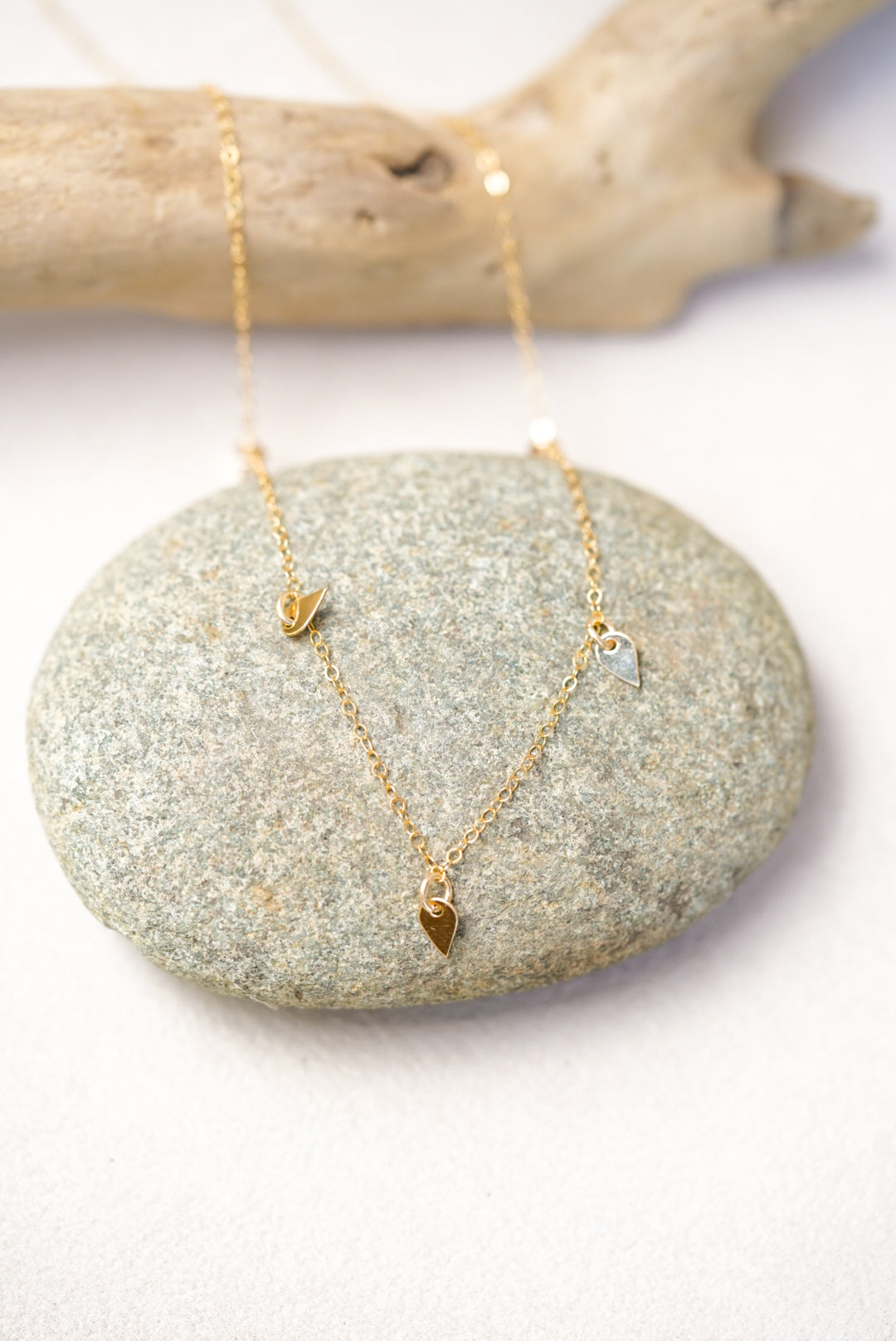 Gold necklace with sequin pendants on a stone surface