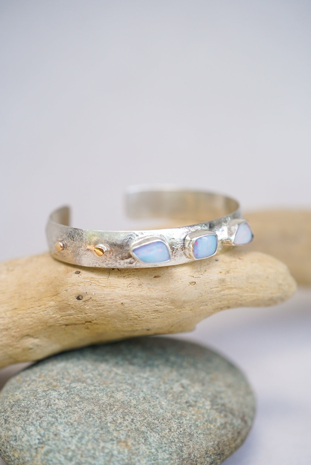 Silver bracelet with opal stones on a stack of pebbles