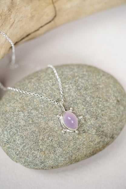 purple pendant necklace on top of a river rock
