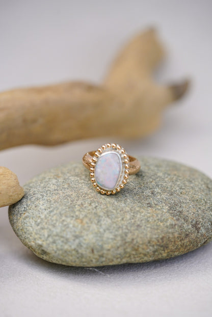 Gold ring with a opal stone on a gray stone surface