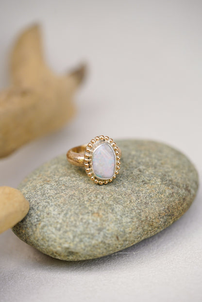 Gold ring with a opal stone on a gray stone surface