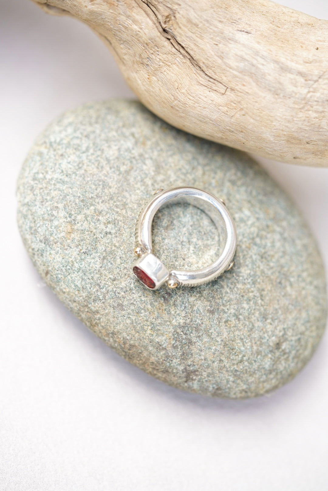 Bright red sunstone silver ring on a piece of river rock