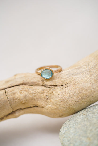 Aquamarine gold ring on a piece of driftwood