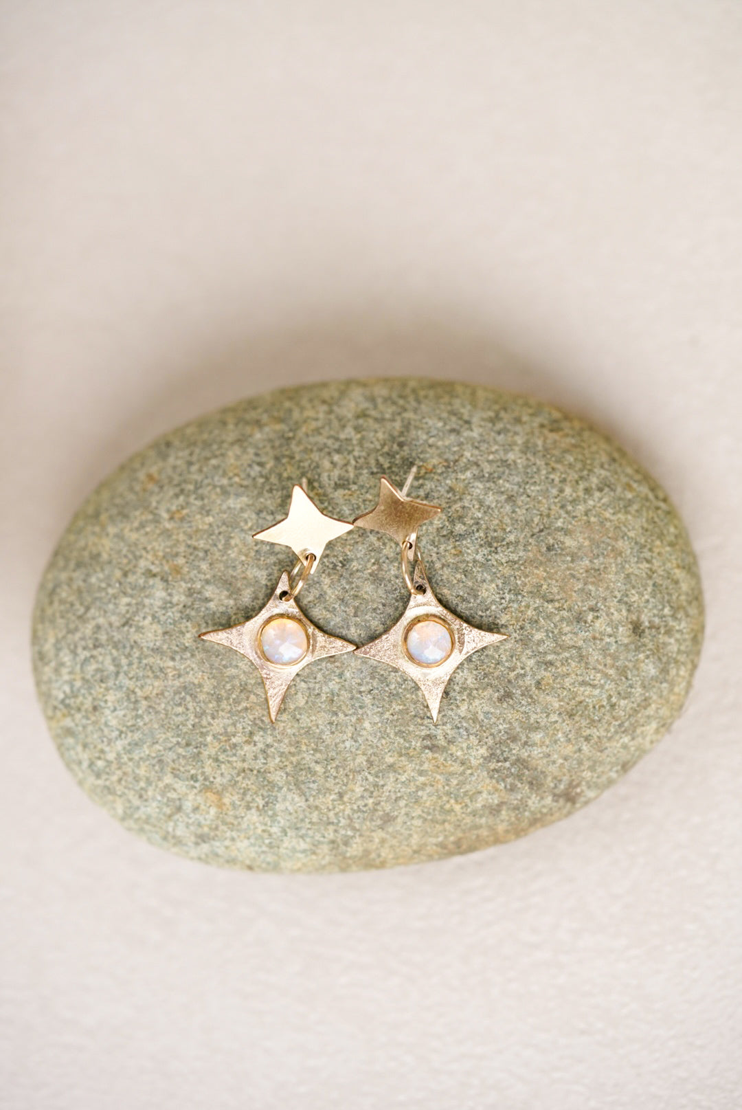Gold earrings with star designs on a stone