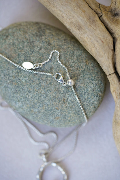 Silver necklace with a pendant on a stone surface