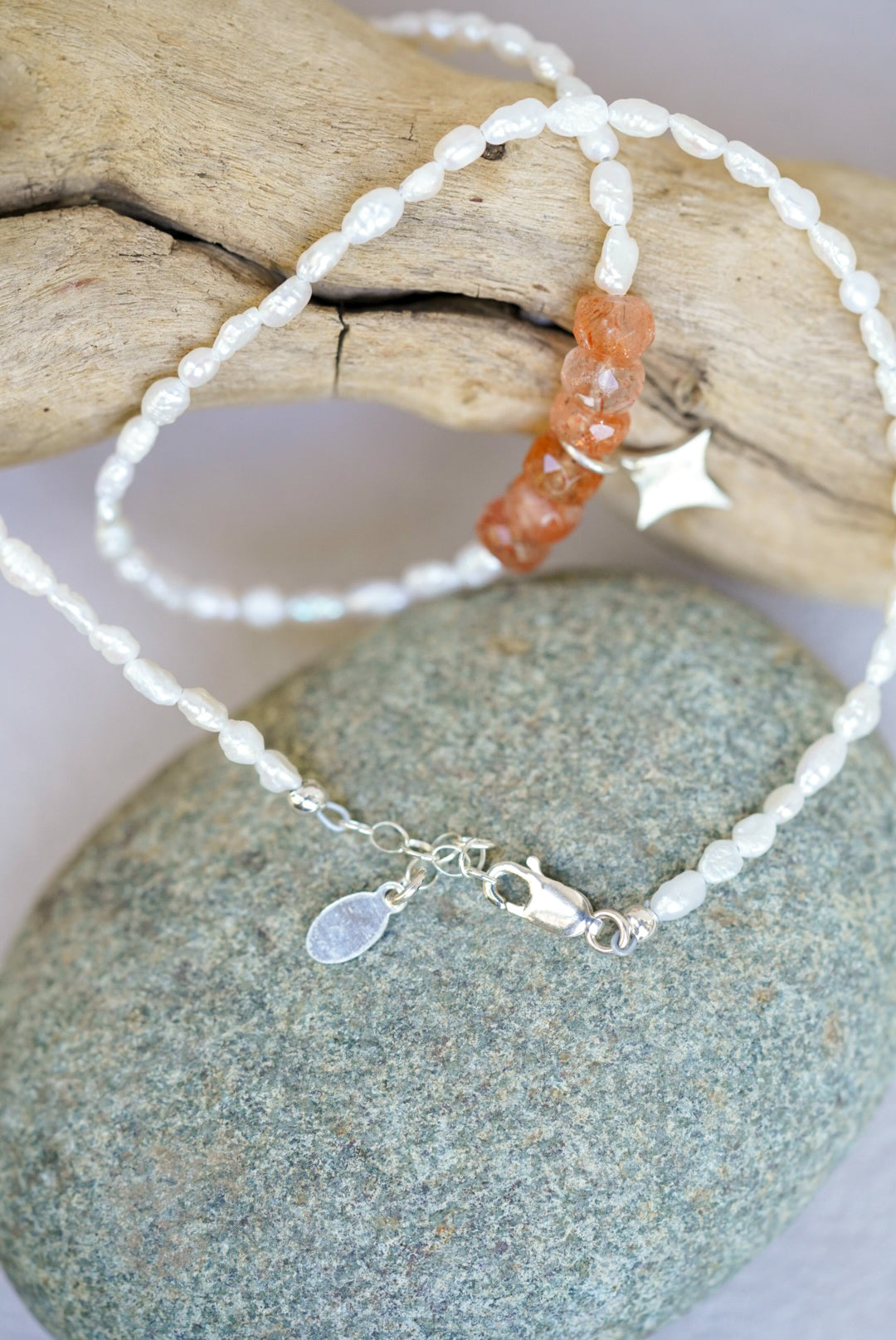 pearl and sunstone necklace on a stone surface with a natural background