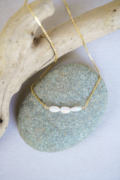 Gold necklace with opal beads on a stone surface