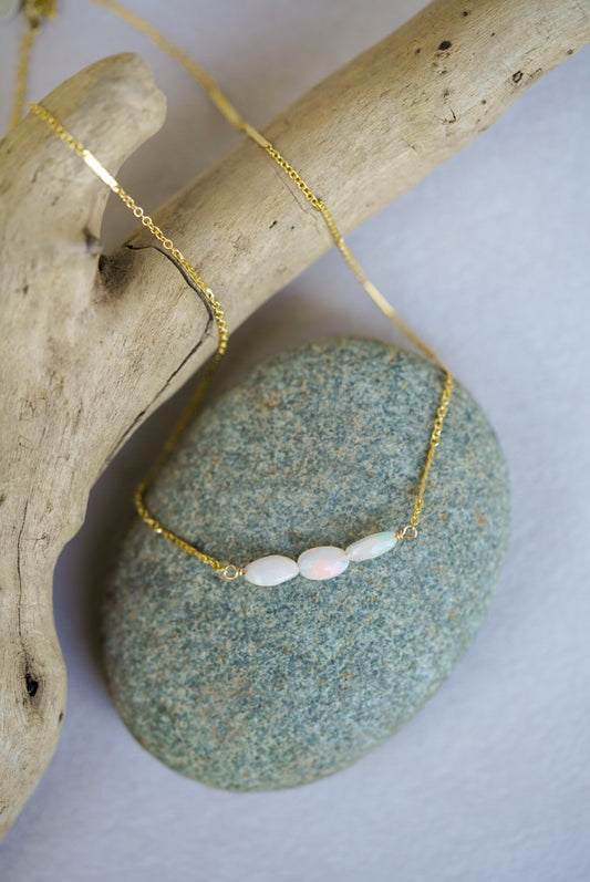 Gold necklace with opal beads on a stone surface