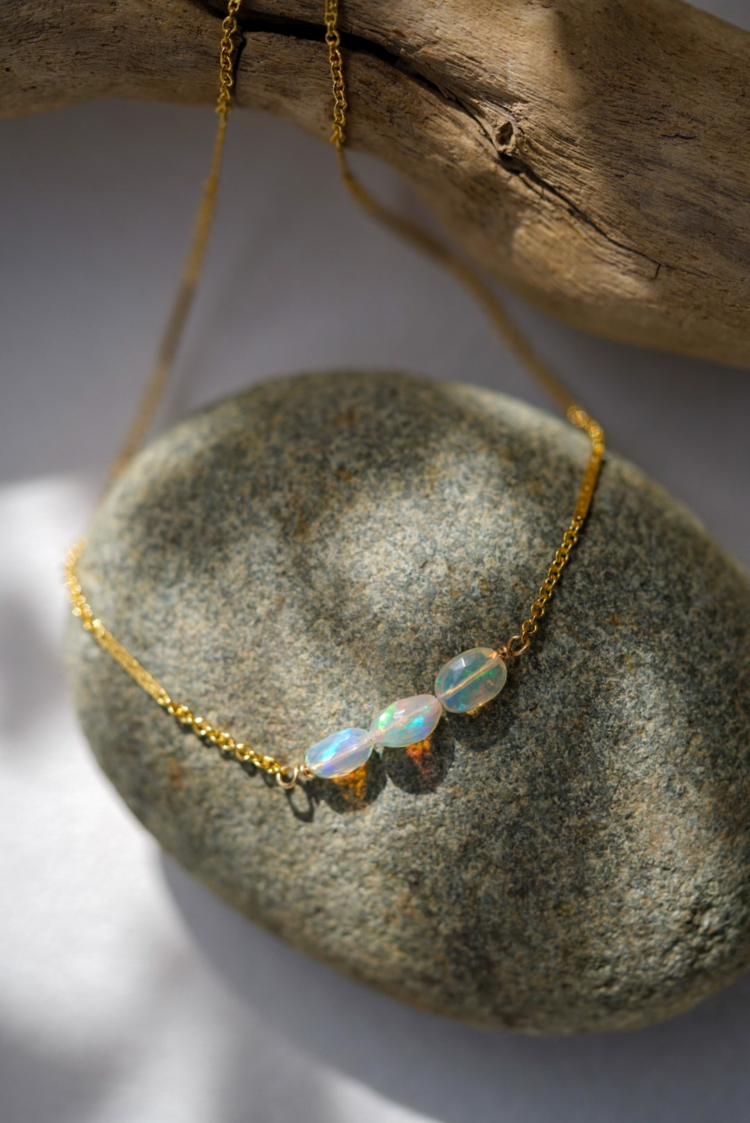 Gold necklace with opal beads on a stone surface