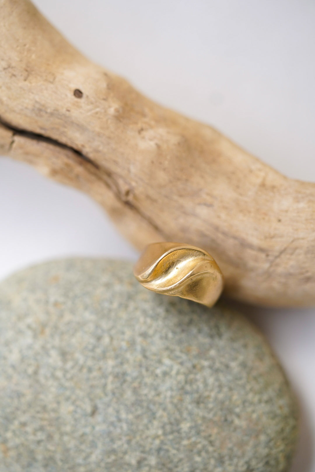 Gold ring on a stone with a wooden branch in the background