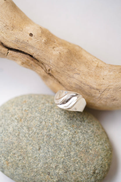 Silver ring on a stone with a wooden branch in the background