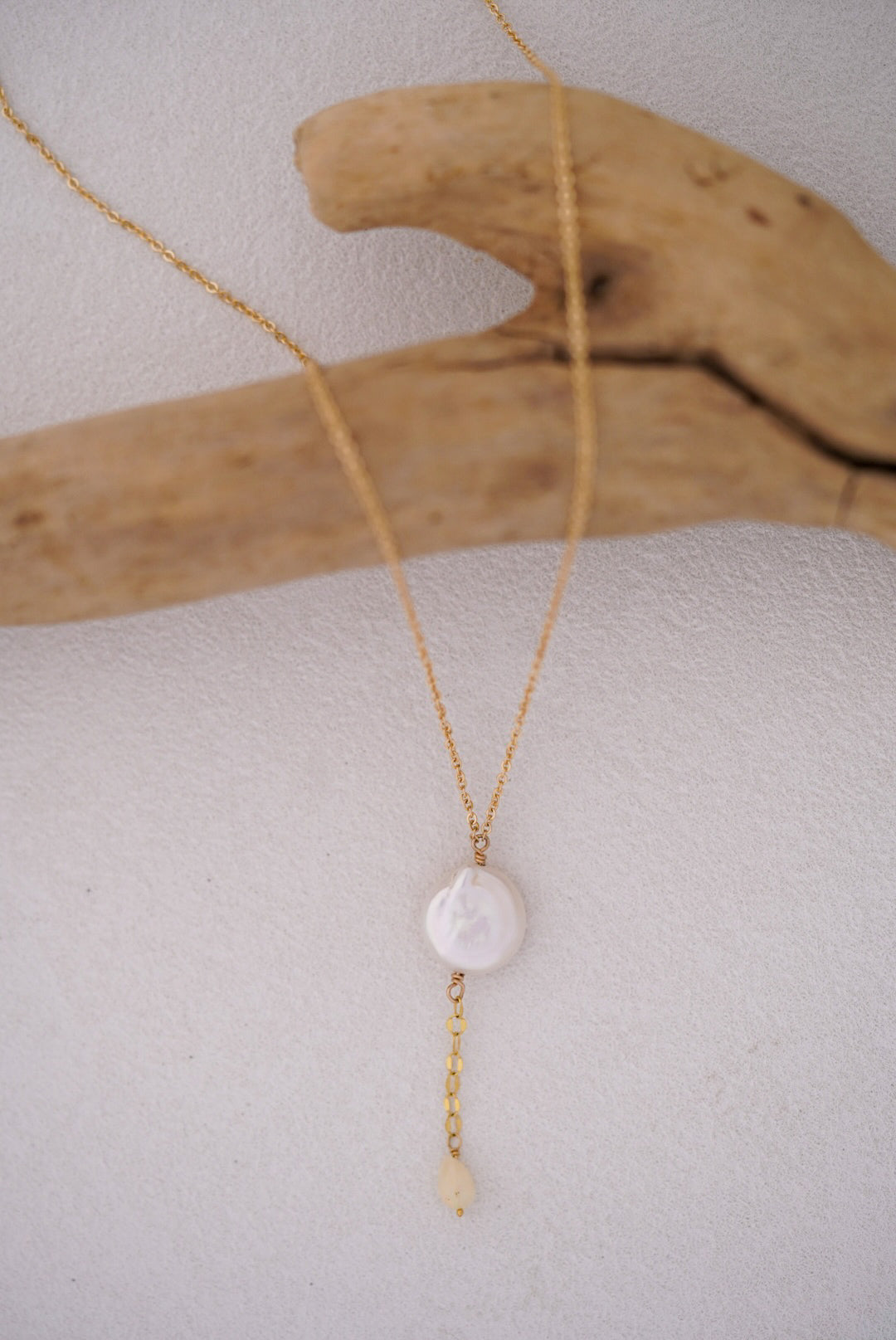 Gold necklace with a pearl pendant on a light white background