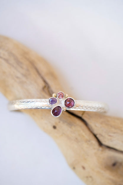 Silver cuff with gemstones on a piece of driftwood