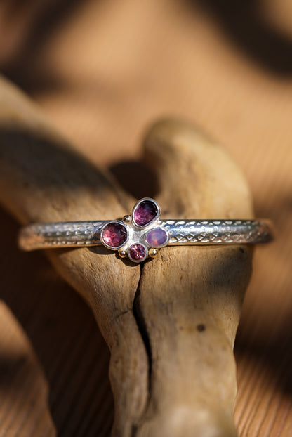 Silver cuff with purple gemstones on a wooden surface