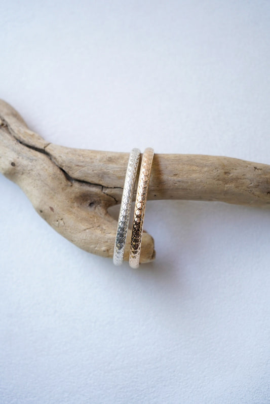 two stamped bracelets on driftwood