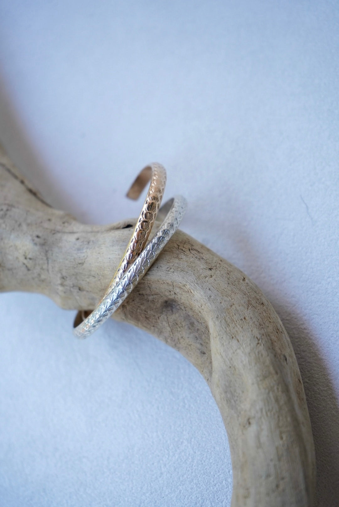 two stamped bracelets on driftwood