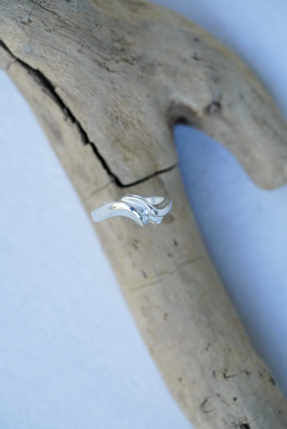 Silver ring on a piece of driftwood with a white background