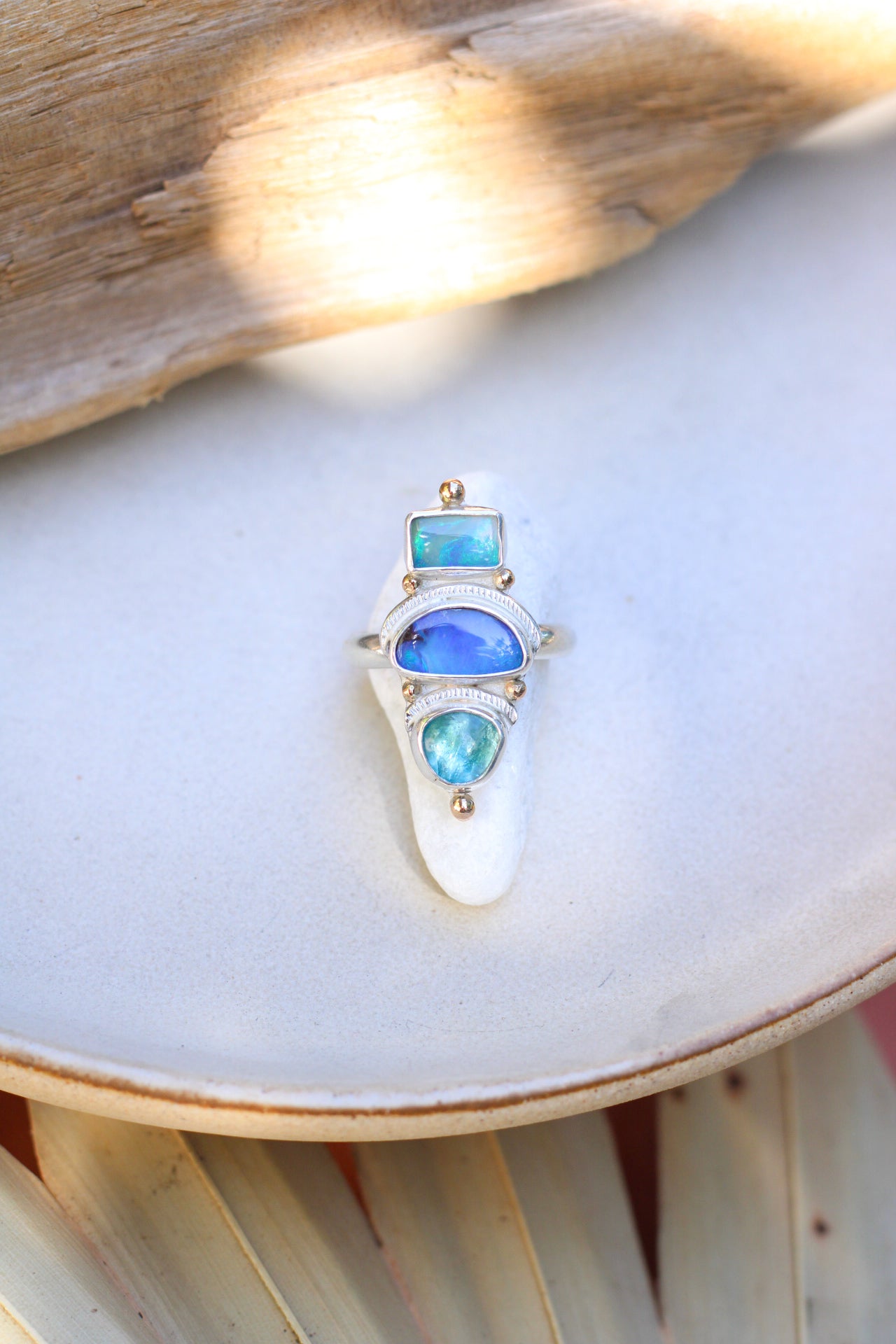 Ring with opal and apatite stones on a white surface