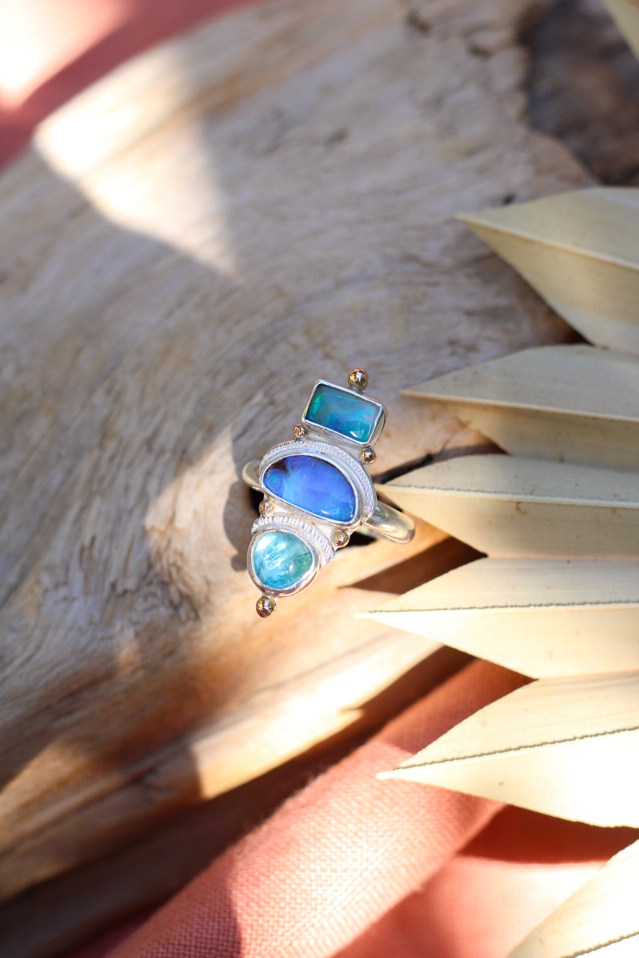 Silver ring with opal and apatite stones on a wooden surface