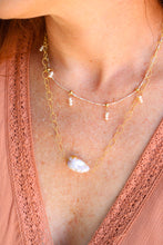 Load image into Gallery viewer, Layered gold necklaces with a pearls on a person wearing a pink lace top.
