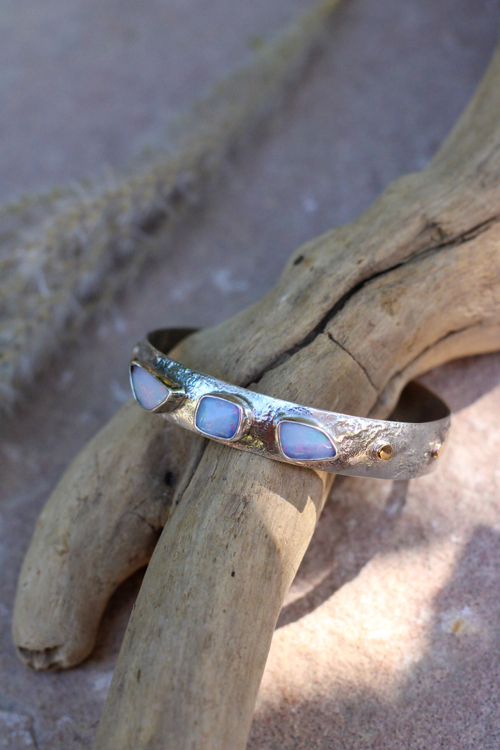 Wide silver opal cuff with texture and small gold details.