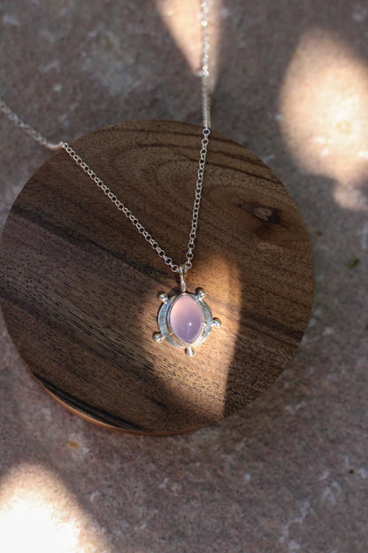 Necklace with a purple chalcedony  pendant on a wooden surface