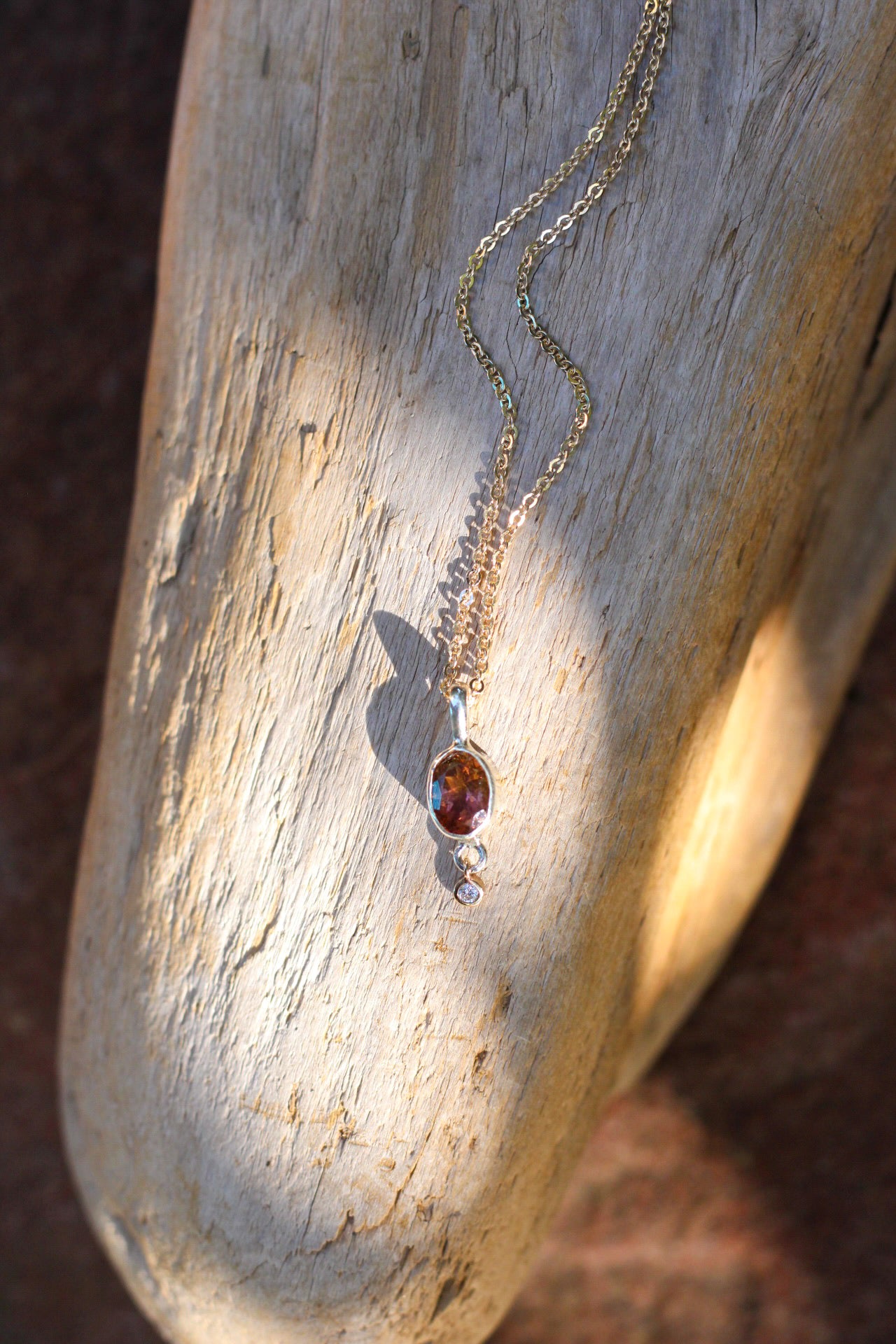 Necklace with a tourmaline and diamond pendant on a textured wooden surface