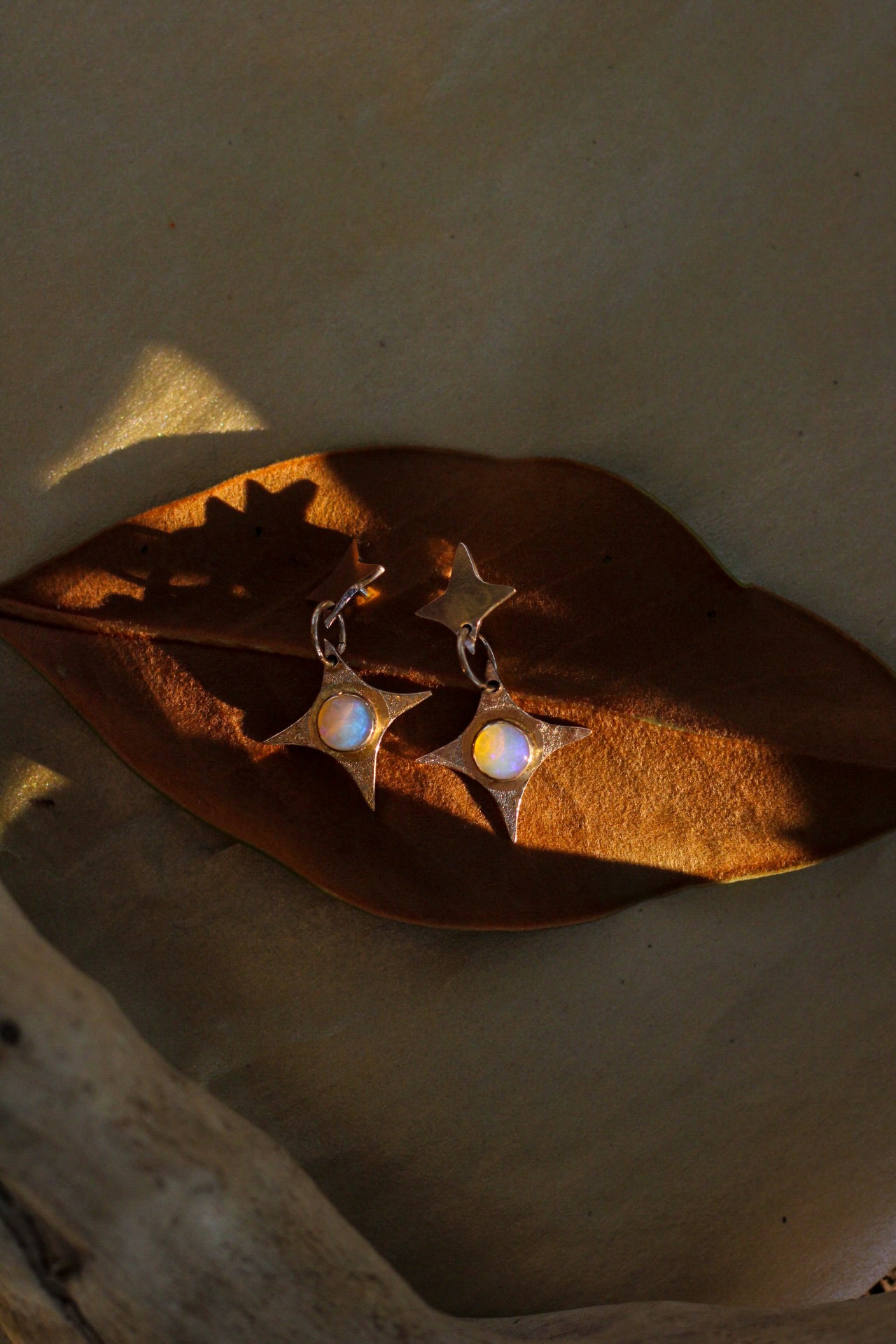 Pair of earrings with opal stones on a leaf