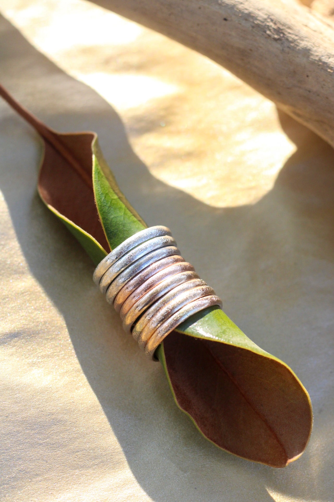 Silver, gold and rose gold rings layered bands on a leaf