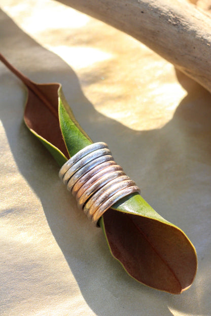Silver, gold and rose gold rings layered bands on a leaf
