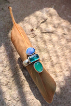 Load image into Gallery viewer, Ring with blue and green stones on a brown leaf against a stone background
