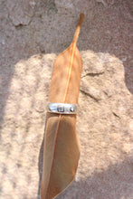 Load image into Gallery viewer, Silver ring on a brown leaf against a textured stone background
