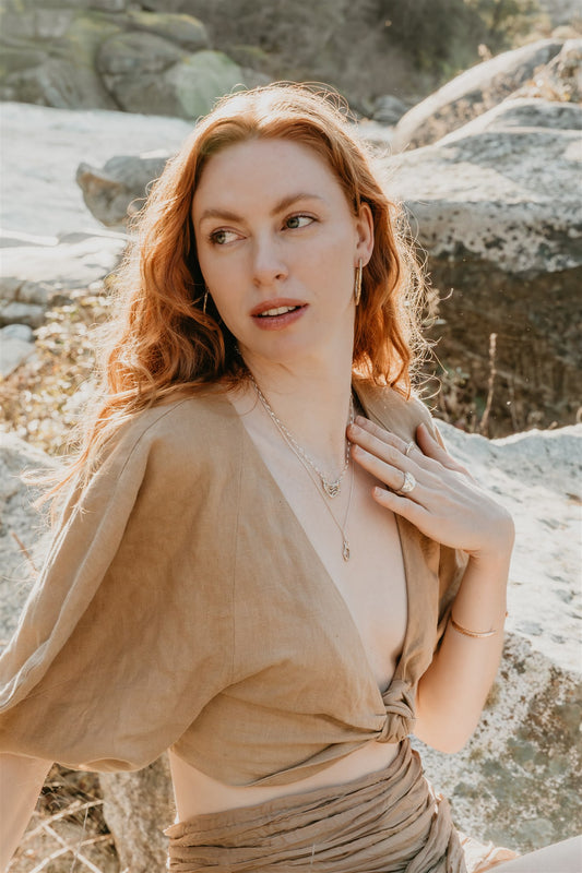 Woman with jewelry, outdoors near rocks
