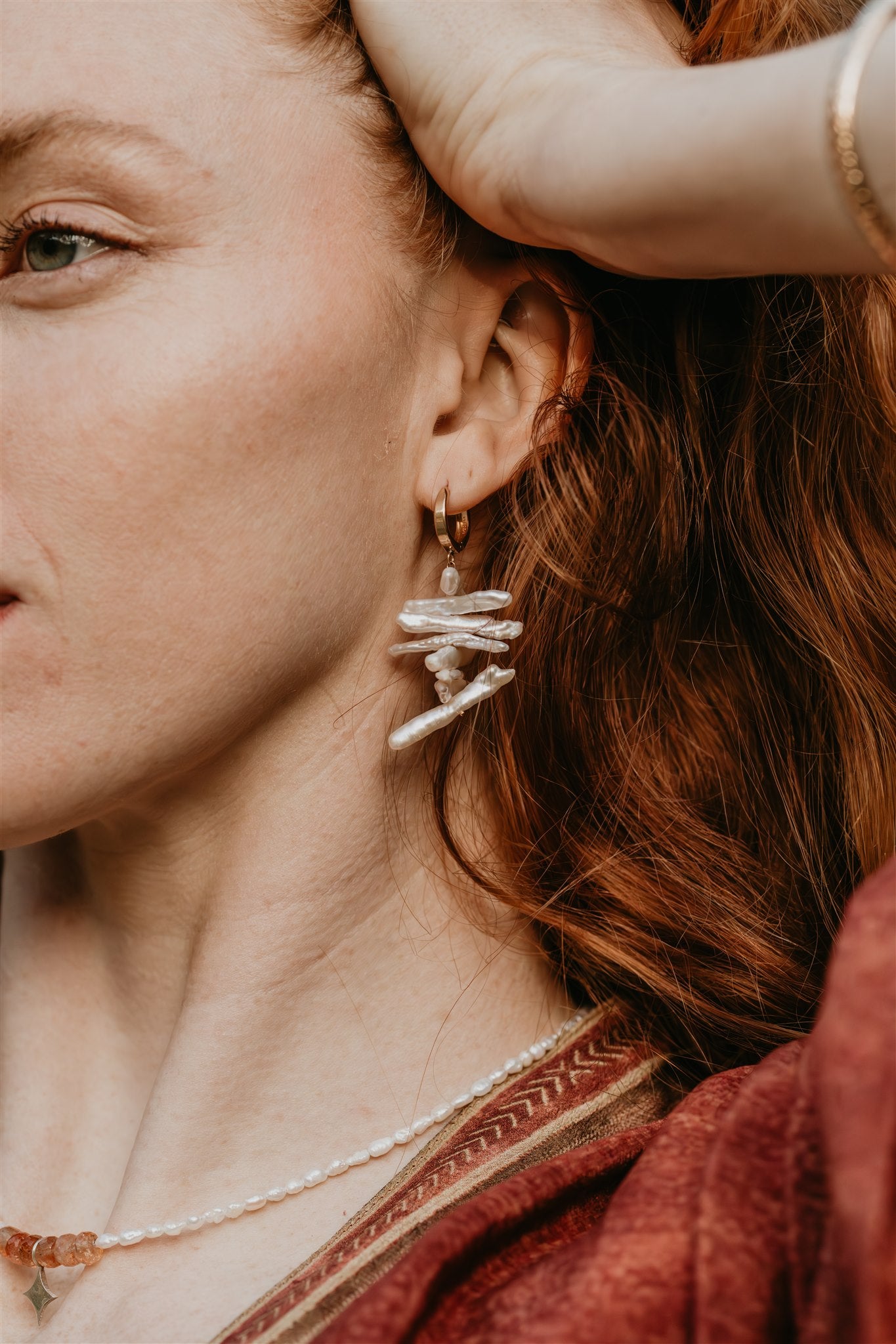 Close-up of a person wearing a pearl earring with a blurred background