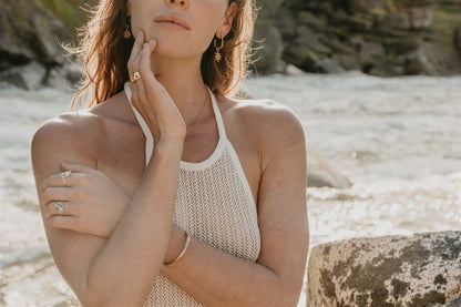Woman in a white sleeveless top by a river with blurred natural background