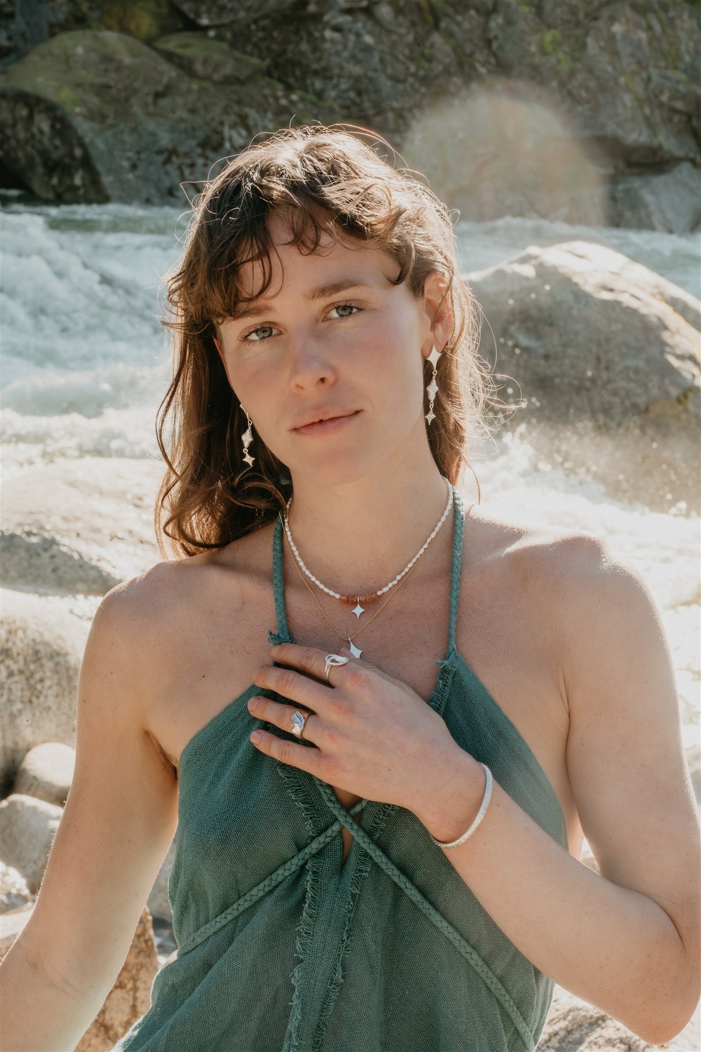 Woman in a green dress standing by a rocky water source