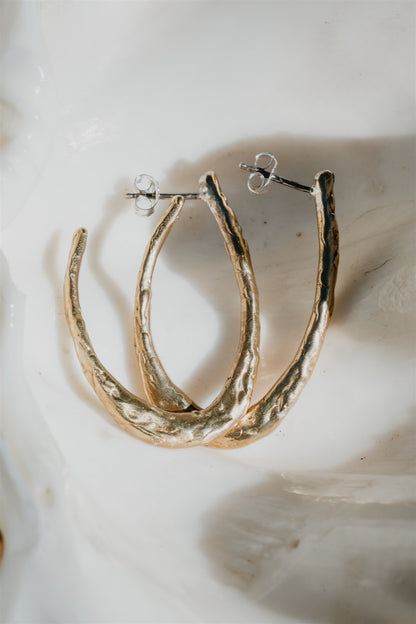 Gold hoop earrings on a textured white surface