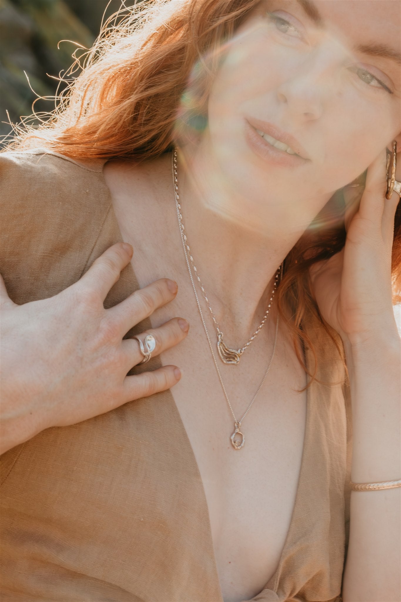 Woman wearing gold and silver jewelry with a blurred background